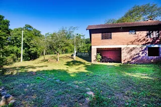Fachada de uma casa com jardim e vegetação ao redor.