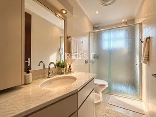 Banheiro moderno com box de vidro e bancada de mármore.