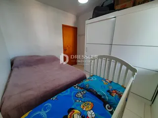 Quarto com cama e armários brancos em um imóvel em Lajeado.