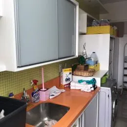 Foto de uma cozinha com bancada laranja e azulejos amarelos na área de preparo.