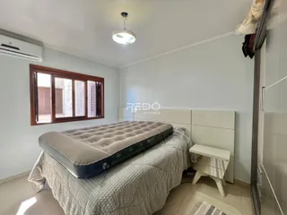 Quarto com cama e janela em ambiente claro.
