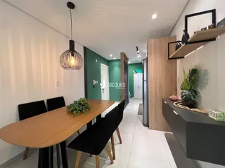 Imagem de uma sala de jantar moderna com mesa de madeira e cadeiras pretas.