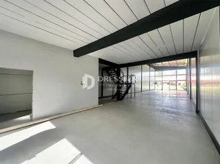 Espaço interno amplo com teto inclinado e vigas escuras.