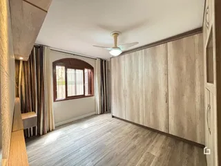 Quarto com armários em madeira e janela no interior de uma residência.