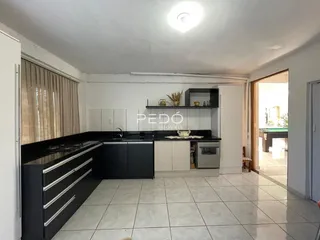 Vista da cozinha com armários escuros e piso claro.