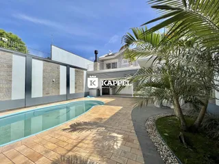 Foto da área externa com piscina e paisagismo.