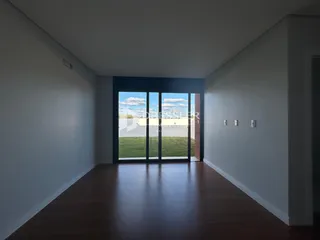 Vista de um corredor interno com piso de madeira e portas de vidro.