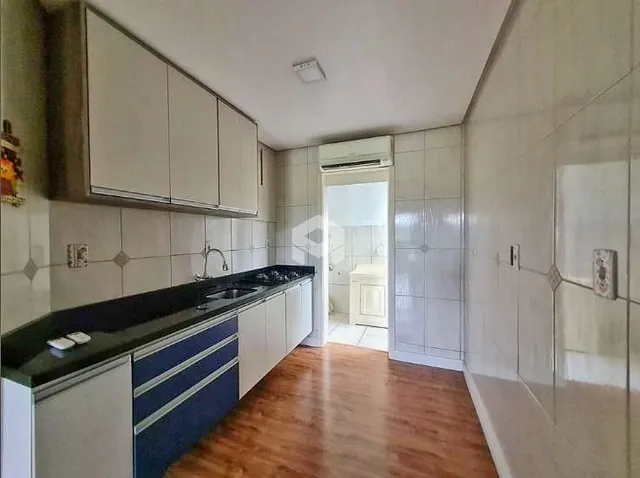 Cozinha com armários brancos e piso de madeira.