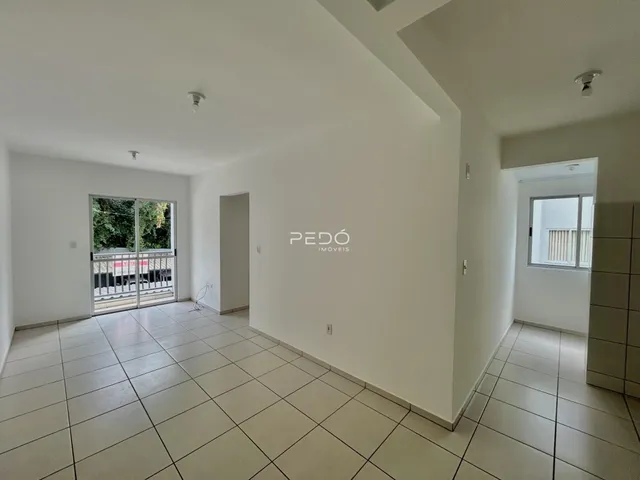 Ambiente interno de uma sala com piso de cerâmica e paredes brancas.