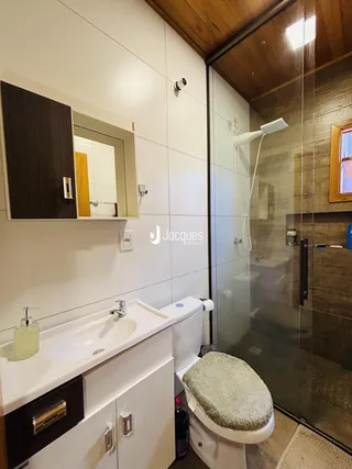 Foto de um banheiro moderno com box de vidro e louças brancas.