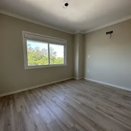 Foto de um cômodo interno com piso de madeira e janela.