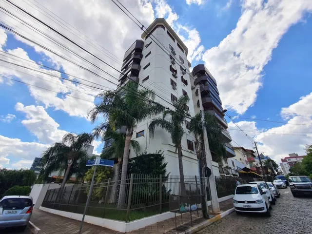 Fachada de um prédio residencial em Lajeado, Brasil, com vegetação e céu azul.