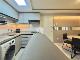 Vista da cozinha moderna com ilha e área de jantar em um imóvel no Brasil.