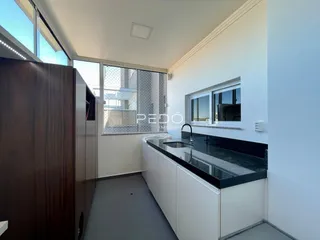 Vista da cozinha moderna com bancada escura e janelas amplas.