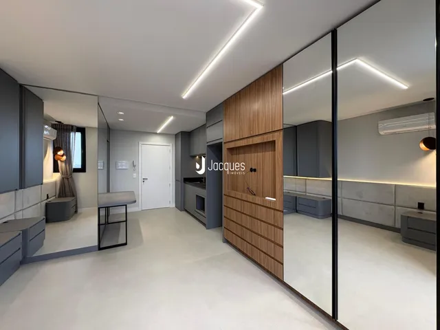 Sala de estar e cozinha moderna com armários cinzas e piso claro.