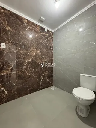 Foto de um banheiro com revestimento de mármore marrom escuro e piso claro.