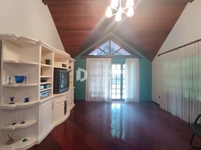 Sala de estar com piso de madeira e teto inclinado em uma residência.