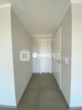 Foto de um corredor interno com paredes brancas e piso claro.