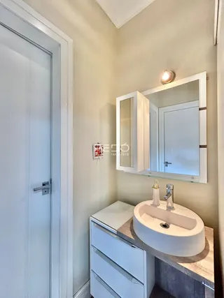 Banheiro com bancada branca e espelho instalado.