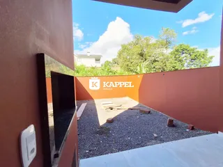 Vista de um pátio externo com piso de cascalho e muro de cor laranja.