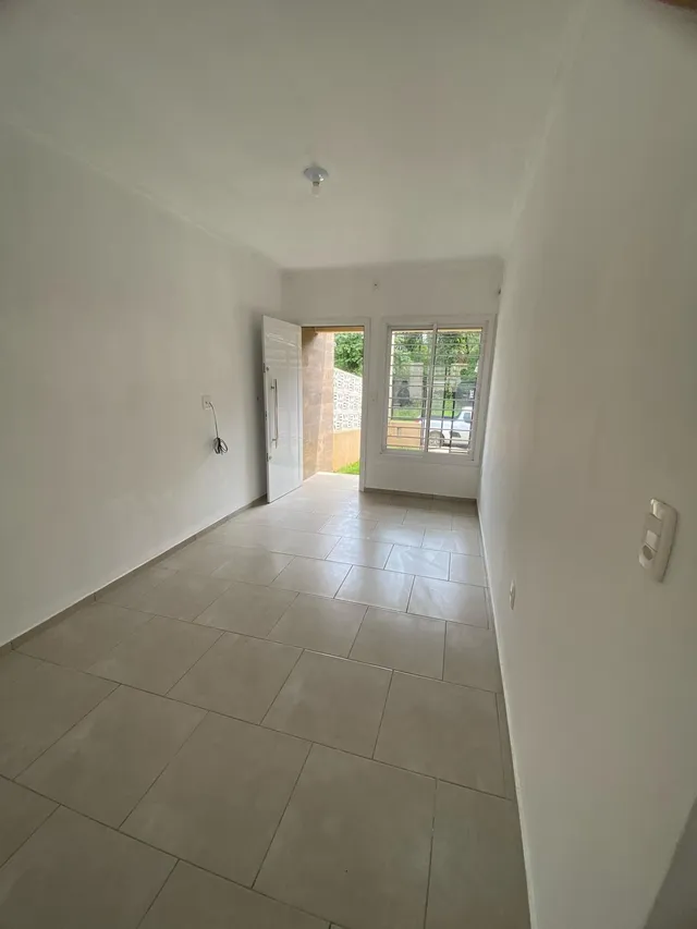 Uma foto de um corredor interno com piso de cerâmica claro e uma porta branca.