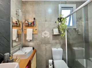 Banheiro com box de vidro e bancada de madeira.