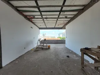 Imagem de um espaço interno em construção com vigas expostas.