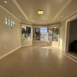 Sala ampla com forro alto e molduras brancas.