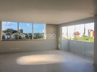 Ambiente interno de uma sala ampla com grandes janelas que oferecem uma vista da paisagem.