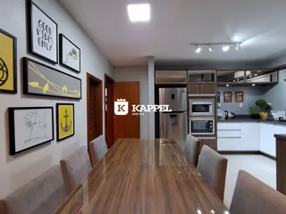 A sala de estar apresenta uma mesa de madeira e uma cozinha moderna.