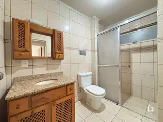 Banheiro com revestimento cerâmico e box de vidro.