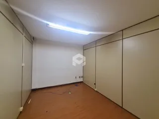 Interior de um cômodo com paredes brancas e piso marrom.