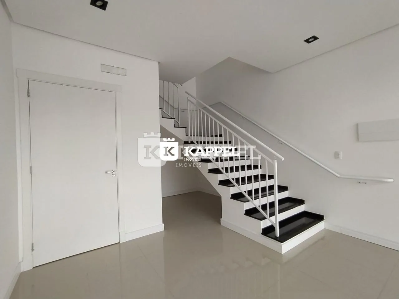 Hall de entrada com escadaria branca e piso claro.