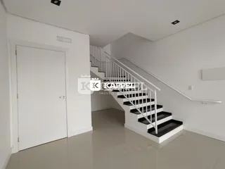 Hall de entrada com escadaria branca e piso claro.