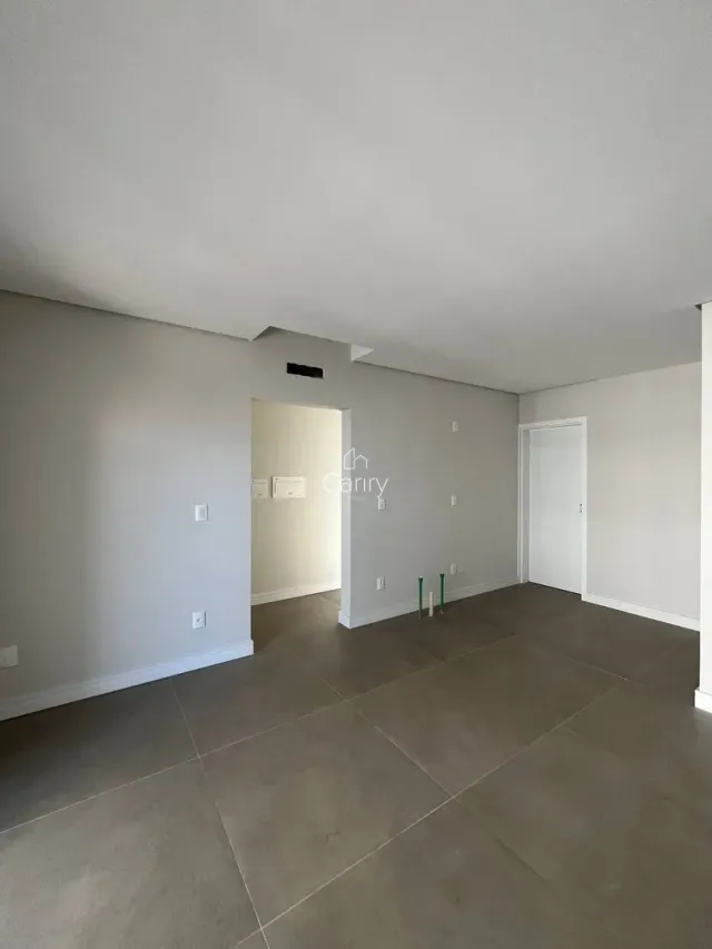 Vista interna de um ambiente amplo com piso de porcelanato cinza e paredes brancas.
