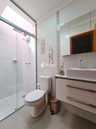 Banheiro moderno com box de vidro e louças brancas.