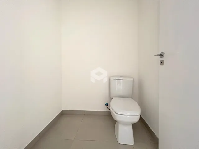 Foto de um banheiro com paredes brancas e piso de cerâmica.