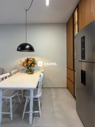 Uma mesa de jantar branca com cadeiras brancas e um arranjo floral em um ambiente interno.