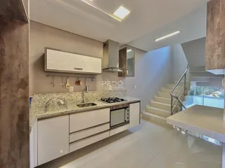 Vista da cozinha moderna com bancada de granito e acesso à escadaria.