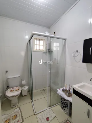 Foto de um banheiro com box de vidro e vaso sanitário branco.