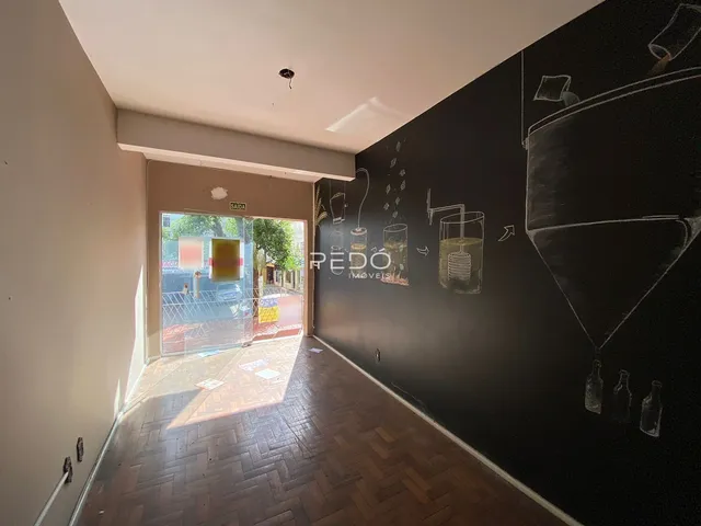 Hall de entrada com piso de madeira e parede escura em uma residência.