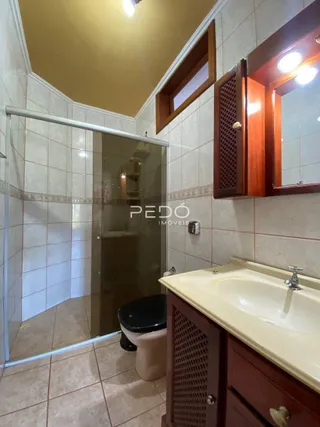 Foto de um banheiro com revestimento cerâmico e box de vidro.