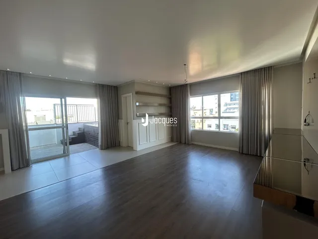 Sala de estar ampla com piso de madeira e grandes janelas.