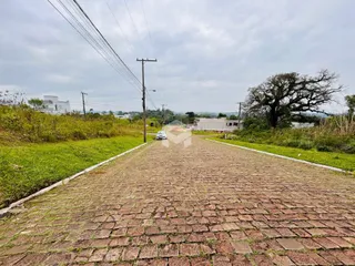 Uma estrada pavimentada com pedras se estende por uma propriedade com gramados nas laterais.