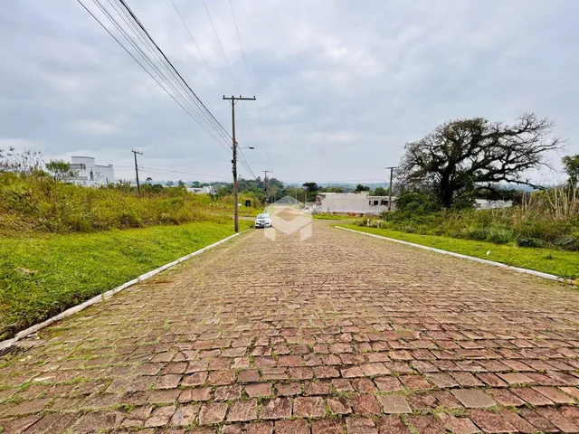 Uma estrada pavimentada com pedras se estende por uma propriedade com gramados nas laterais.