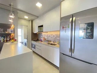 Vista da cozinha moderna com armários brancos e eletrodomésticos de aço inoxidável.