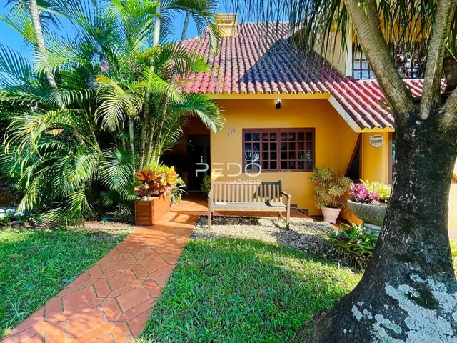 Fachada de uma casa amarela com telhado de telhas vermelhas em Lajeado.
