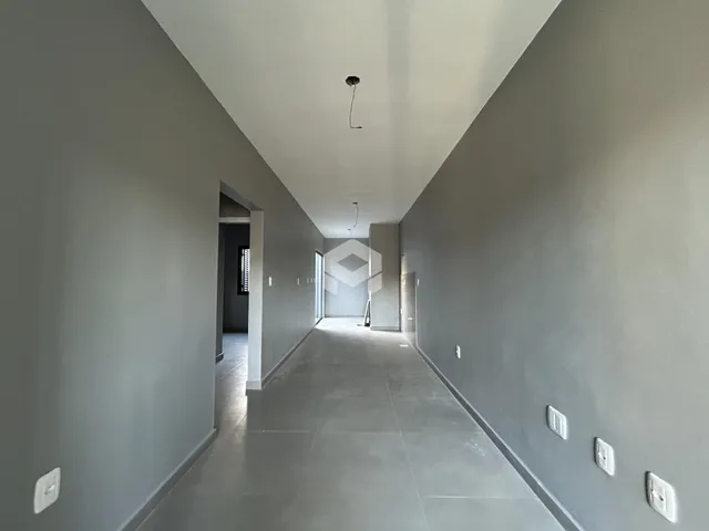 Corredor interno de uma residência com paredes cinzas e piso claro.