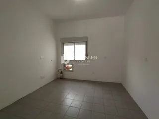 Ambiente interno de uma sala com piso de cerâmica e paredes brancas.