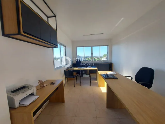 Ambiente interno de uma sala de estar com piso de madeira e grandes janelas.